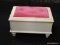 WHITE PAINTED CHILDS STOOL; HAS A PINK BUTTON TUFTED SEAT THAT LIFTS TO REVEAL A STORAGE AREA. SITS