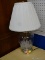 TABLE LAMP WITH ETCHED GLASS BASE; COMES WITH PLEATED OFF WHITE LAMPSHADE. MEASURES 21 IN TALL.