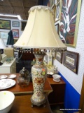 HAND PAINTED TABLE LAMP; THIS LAMP HAS A TAN BELL SHAPED BEADED SHADE SITTING ATOP A URN SHAPED HAND
