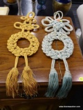 WOVEN TASSEL WALL DECOR; 1 IS SAGE GREEN AND 1 IS AMBER IN COLOR. BOTH HAVE CLOVER LEAF WOVEN