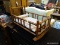 (R4) ROCKING DOLL CRADLE; HAS MAHOGANY BONES WITH TURNED POST FRAME AND A FLORAL CUSHION WITH