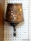 (R1) COPPER COLORED WALL SCONCE/LAMP; EMBOSSED SHADE, AND SCROLLING IRON SEGMENT UNDERNEATH.