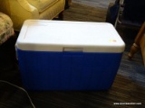 (R4) BLUE COLEMAN COOLER; HAS A WHITE TOP WITH A BLUE BODY AND 2 WHITE SIDE HANDLES. MEASURES 23 IN
