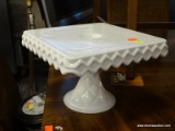 (R4) CAKE PLATE; MILK GLASS SQUARE CAKE PLATE WITH PEDESTAL BASE AND DIAMOND PATTERN EDGING.