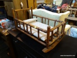 (R4) ROCKING DOLL CRADLE; HAS MAHOGANY BONES WITH TURNED POST FRAME AND A FLORAL CUSHION WITH