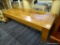 COFFEE TABLE; MISSION STYLE OAK COFFEE TABLE WITH 4 IN BANDED TOP. MEASURES 55 IN X 22 IN X 15 IN