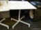 METAL TILT TOP TABLE; ONE OF A PAIR OF WHITE METAL TABLES. SQUARE TOP WITH HANDLE THAT WILL FOLD THE