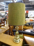 BRASS TONED TABLE LAMP; GREEN AND TAN BURLAP, DRUM SHAPED SHADE SITTING ON A BRASS CANDLESTICK STYLE