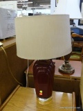 VINTAGE TABLE LAMP; DRUM SHAPED TAN SHADE SITTING ON A BURGUNDY BODY WITH A ROUND BRASS TONED BASE.