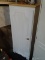 WHITE STORAGE CABINET UNIT; THIS UNIT HAS A LIGHT WOODGRAIN TOP, SINGLE FRONT CABINET DOOR WITH