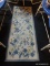 FLORAL AREA RUG; CREAM COLORED MACHINE MADE RUNNER RUG WITH BLUE AND LIGHT YELLOW FLOWERS. MEASURES