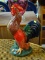 LARGE ROOSTER STATUE; LARGE CERAMIC MULTI-COLORED ROOSTER STANDING IN GREEN GRASS. MEASURES 14 IN.