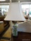 TABLE LAMP; 1 OF A PAIR OF GREEN FLORAL TABLE LAMPS WITH WHITE RECTANGULAR SHADES AND BRASS FINIALS.