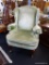 GREEN UPHOLSTERED WING CHAIR; HAS CREAM COLORED TRIM AND MAHOGANY BONES WITH QUEEN ANNE LEGS AND