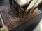 HAND MADE ORIENTAL STYLE RUG; HAS A FLORAL PATTERN IN BURGUNDY, GREEN, AND OFF-WHITE. MEASURES 8 FT