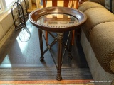 ROUND METAL END TABLE; HAS A GLASS INSERT AND PAW STYLE FEET. HAS A BRONZE TONED RIM WITH BRASS