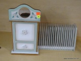 FILE ORGANIZER; HAS A FLORAL THEME WITH WHITE AND LIGHT GREEN COLORING. HAS A SINGLE DOOR THAT OPENS