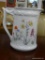 PHILIPPE DESHOULIERES PITCHER; LOURIOUX EDITION WITH FLORAL DESIGN. MEASURES 7.5 IN X 4 IN X 7.5 IN.