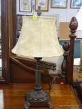 ADJUSTABLE METAL TABLE LAMP; FEATURES A METAL FINIAL, A BEIGE BELL LAMP SHADE, ADJUSTABLE ARM, BRUSH