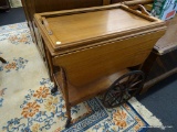 ROLLING TEA CART; OAK ROLLING TEA CART WITH DROP SIDES AND LOWER SHELF. HAS A DOUBLE HANDLED TRAY