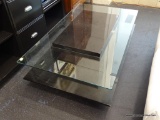 MID-CENTURY MODERN COFFEE TABLE; FEATURES A BLACK SQUARE BASE IN THE CENTER WITH A RECTANGULAR GLASS