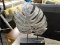 METALLIC LEAF DECOR PIECE; LARGE BRUSHED SILVER TONE LEAF SITTING ON A PAINTED BLACK RECTANGULAR