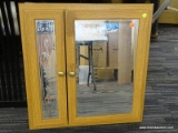 MIRRORED VANITY CABINET; LIGHT WOOD GRAIN DOUBLE DOOR CABINET WITH BEVELED MIRRORS. THE LEFT SIDE