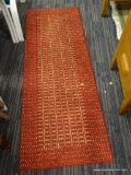 WOVEN FLOOR RUNNER. NEUTRAL TONES OF WARM RED WITH MULTICOLORED DESIGN IN GRAY, TAUPE, AND TAN.