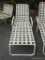 OUTDOOR WHITE ALUMINUM & VINYL CROSS STRAP CHAISE LOUNGE; ADJUSTABLE BACK. IN GOOD USED CONDITION.