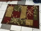 AREA RUG; MACHINE MADE BROWN, TAN, BURGUNDY, AND GREEN AREA RUG WITH TAN COLORED VINES AND LEAVES.
