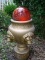 (OUT) DECORATIVE ORB ON STAND; RED GLASS ORB MOUNTED ATOP A GOLD PAINTED LIONS HEAD THEMED BASE. IS