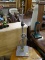 METAL LAMP; 2FT 8IN TALL, SQUARE BASE 8.5IN WIDE. GREY WITH A SPIRALING DECORATION POINTING UP.