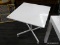 METAL TILT TOP TABLE; ONE OF A PAIR OF WHITE METAL TABLES. SQUARE TOP WITH HANDLE THAT WILL FOLD THE