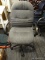 ROLLING OFFICE CHAIR; THICK PADDED GREY BACK AND SEAT ON A BLACK SWIVEL BASE WITH 5 WHEELS. MEASURES