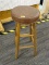 CUSHIONED BARSTOOL; ROUND BROWN VINYL SEAT SITTING ON WOODEN BASE WITH FOOT RESTS. MEASURES 2 FT 5.5