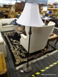 FLOOR LAMP; WHITE BELL SHAPED LAMPSHADE ATOP A POST WHICH IS DARK BRUSHED GREY METALLIC COLOR, WITH