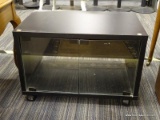 ROLLING TV CART; BLACK RECTANGULAR TV CART WITH TWO GLASS DOORS THAT OPEN TO REVEAL A SHELF FOR