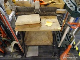 MITRE SAW TABLE; HAS A WOODEN TOP WITH A METAL BASE ON WHEELS AND 1 LOWER SHELF. IS IN GOOD USED