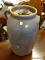 POTTERY JUG; BROWN POTTERY JUST WITH SIDE HANDLE, AND TOP WITH CENTER HOLE. MEASURES 15 IN TALL.