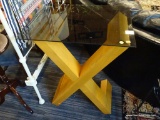 WOODEN X TABLE; A TINTED GLASS TABLE TOP BEING HELD UP BY A LARGE WOODEN X. MEASURES 24 IN X 18 IN X