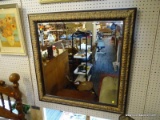 LARGE HANGING MIRROR; LARGE HANGING BEVELED GLASS MIRROR WITH A BRASS TONE MOLDED WOODEN FRAME.