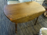 WALNUT LEAF FLIP UP TABLE; ROUND WALNUT TABLE WITH 2 FLIP UP LEAVES. SITS ON 4 TAPERED LEGS.