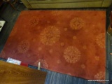 AREA RUG; RUST COLORED 100% WOOL AREA RUG WITH FLORAL DESIGN. MEASURES 6 FT X 8 FT.