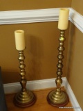 (DR) CANDLE HOLDERS; 2 LARGE BRASS CANDLEHOLDERS ON WOODEN STANDS- 32 IN AND 25 IN TALL