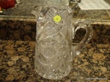 (KIT) CUT GLASS PITCHER; CUT GLASS STARBURST PATTERN WATER PITCHER. MEASURES 9 IN TALL.