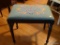 (LR) NEEDLEPOINT FOOTSTOOL; BLUE FLORAL NEEDLEPOINT FOOTSTOOL WITH A WOODEN BASE THAT HAS 4 TAPERED