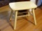 (DR) CREAM PAINTED WOOD STOOL; WOOD GRAIN STOOL PAINTED CREAM WITH AN H STRETCH AND 4 SQUARE LEGS.