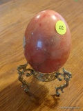 (DR) MARBLE EGG AND STAND; REDDISH/ORANGE LARGE MARBLE EGG ON A GOLD TONE STAND WITH SCROLLING LEGS.