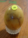 (DR) MARBLE EGG AND STAND; ORANGE, BROWN, AND YELLOW LARGE MARBLE EGG ON A GLASS STAND.