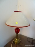 (LR) CRANBERRY GLASS TABLE LAMP; CRANBERRY GLASS TABLE LAMP SITTING ON A METAL STAND. COMES WITH A